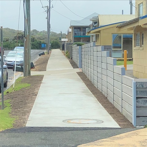 A new footpath that is travelling up a slight hill. There are houses to the right and a road to the left with a silver car parked. 